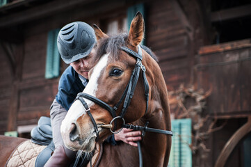 Portrait of a jockey standing by horse in stable