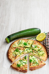 Vegetarian pizza with zucchini and pine nuts on white wooden table