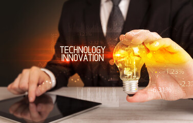 Businessman holding lightbulb with TECHNOLOGY INNOVATION inscription, Business technology concept
