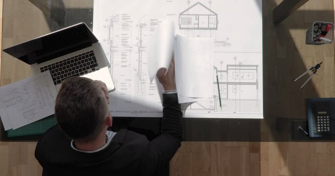 Zoom out top view shot of an architect throws documents in the air and is desperated with floating sun shot in 4k