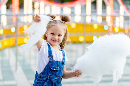 Happy Baby Girl Eating Cotton Candy At Amusement Park In Summer