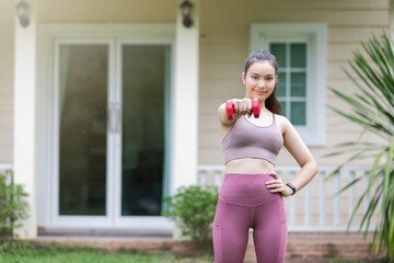 Female fitness instructor exercising with small dumbbell on frontyard.