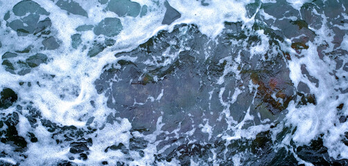 Froth and foam on dark turbulent water, panoramic frame.