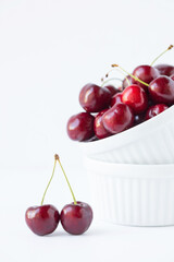 Original food photograph of fresh red cherries in white stacked ramekins on white 