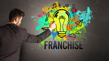 businessman drawing colorful light bulb with FRANCHISE inscription on textured concrete wall, new business idea concept