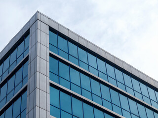 Fototapeta na wymiar Bottom view of modern high rise building against gray sky on cloudy day