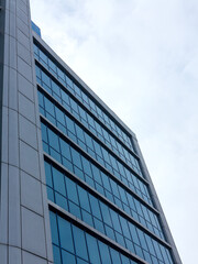 Bottom view of modern high rise building against gray sky on cloudy day