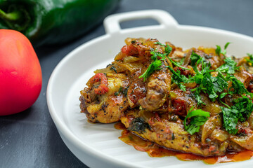 Spicy delicious chicken wings cooked with hot sauce and tomato with caramelized onions topped with chopped cilantro