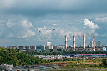 Fototapeta na wymiar Helicopters over the city. Helicopters fly over an industrial area on the outskirts of Moscow