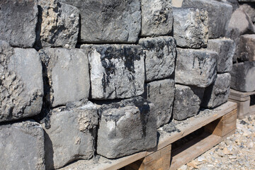 Bauschutt auf der Baustelle: Alte und durch Asphalt verunreinigte Kopfstein Pflastersteine aus Granit zur Entsorgung als Sondermüll und späterem Recycling