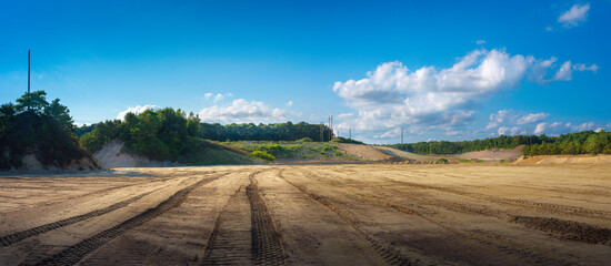 Panoramic landscape of bulldozed land in the forest with cloudy blue sky on the backgrounds © Naya Na