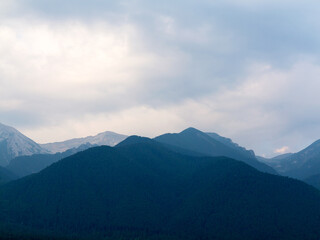 Evening mountain landscape at sunset. Silhouettes of the Pyrenees mountains and the cloudy sky are highlighted by the sun behind the mountains.
