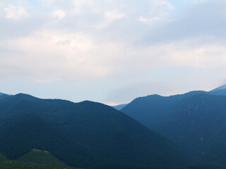 Evening mountain landscape at sunset. Silhouettes of the Pyrenees mountains and the cloudy sky are highlighted by the sun behind the mountains.
