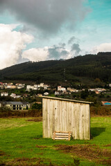 Una peque&ntilde;a caba&ntilde;a en el campo con una monta&ntilde;a y casas al fondo.