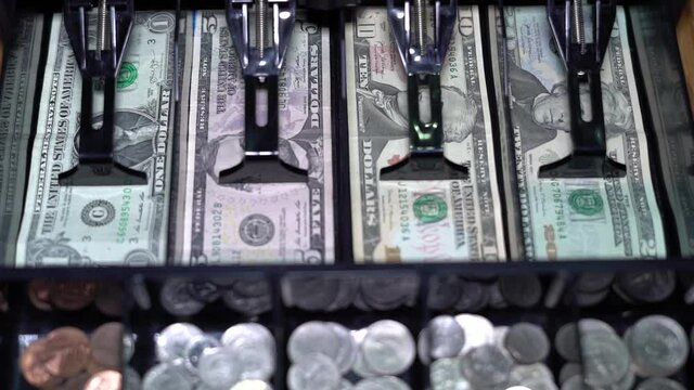 Cash register opening with us currency and coins.