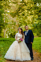 Newlyweds walk in the park and pose for a photographer