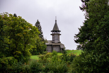 old wooden church on the island between trees in the rain