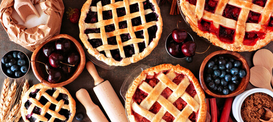 Baking scene with a variety of homemade fruit pies. Top view over a wood banner background. - obrazy, fototapety, plakaty
