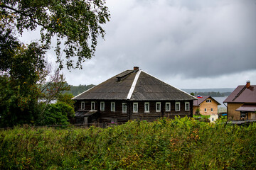 Fototapeta na wymiar old wooden church on the island between trees in the rain