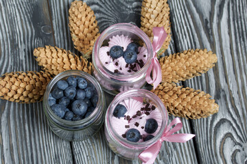 Fototapeta premium Zephyr in a jar, decorated with blueberries. Nearby are fir cones.