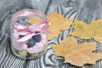 Zephyr in a jar, decorated with blueberries and dried maple leaves. On painted pine planks.