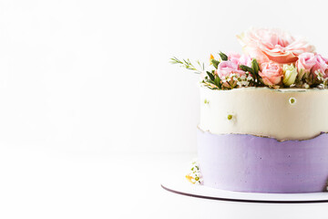 White and violet wedding cake decorated with flowers on the white background