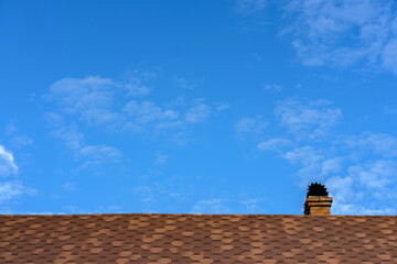 The roof of the house with soft tiles against the sky.