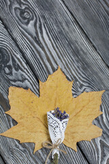 A dried maple leaf and a lavender bouquet on brushed black and white pine boards.
