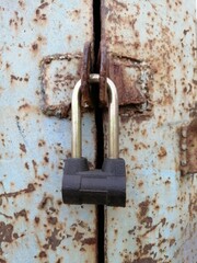new closed padlock locks the hinges of the old rusty iron door