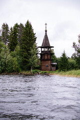 Obraz premium old wooden church on the island between trees in the rain