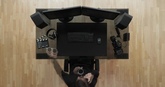 Timelapse top view shot of filmmaker working with two screens post production drinking coffe  shot in 4k