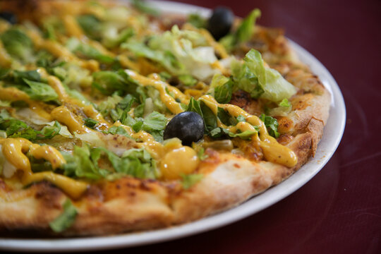 Indian style pizza with chicken and curry sauce and lettuce leaves