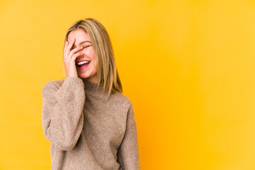 Young blonde caucasian woman isolated on yellow background laughing happy, carefree, natural emotion.