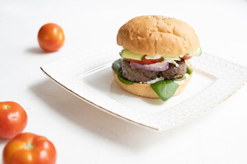 Milanese burger, with tomatoes, lettuce and french fries, in white background