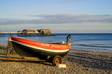 Traditional crab fishing boat on Cromer beach early morning. In the distance is the Victorian era pier, a must see in this seaside town.