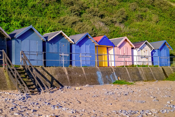 A row of colourful wooden beach huts on Cromer beach on the North Norfolk coast captured at sunrise. 