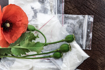 flowers and heads of opium poppy next to packages of heroin, soft focus, tinting, selective bleaching, enhanced contrast