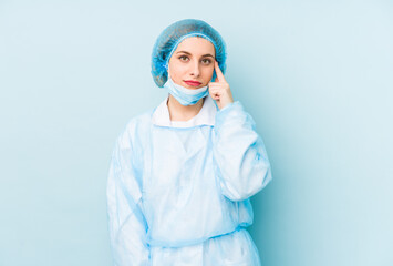 Young surgeon woman isolated pointing temple with finger, thinking, focused on a task.