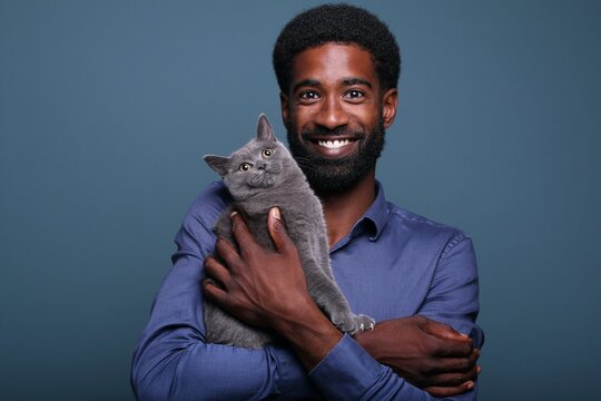 Beautiful afro man with a cute cat in front of a background