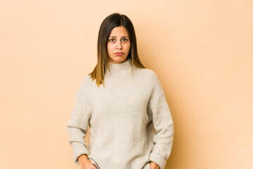 Obraz premium Young woman isolated on beige background blows cheeks, has tired expression. Facial expression concept.