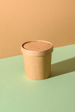 Craft paper soup cup on green and brown paper background. Take away food. Ecological individual package. Zero Waste. Recycling disposable cup. Creative minimal style.