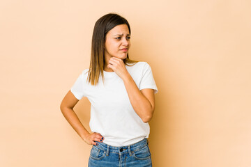 Young woman isolated on beige background suffers pain in throat due a virus or infection.