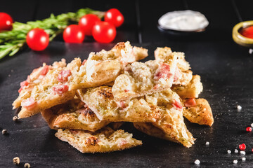 Traditional Italian focaccia among tomato and spices on a dark background, studio light. Traditional food concept