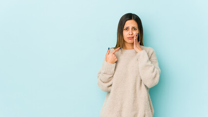 Young woman isolated on blue background having a strong teeth pain, molar ache.