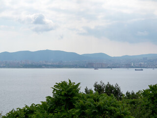 Silhouettes of city buildings and seaport on the sea coast. Novorossiysk, Russia.