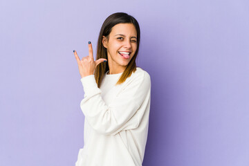 Young woman isolated on purple background showing rock gesture with fingers