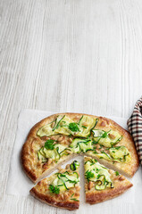 Vegetarian pizza with zucchini and pine nuts on white wooden table
