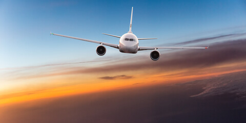Naklejka na ściany i meble Commercial airplane jetliner flying above dramatic clouds in beautiful light. Travel concept.