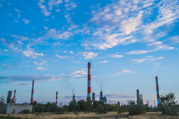 Fototapeta na wymiar Factory pipes against the blue sky. Plant for the extraction and processing of oil. Horizontal photo