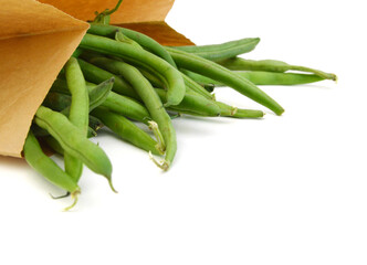 small and slender green beans (haricot vert) in brown paper on a white background